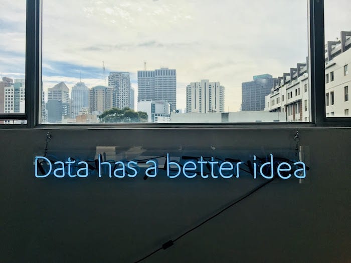 neon sign that reads "data has a better idea." skyline in the background