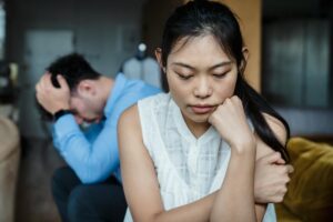 A couple experiencing relationship tension sitting silently on a sofa.