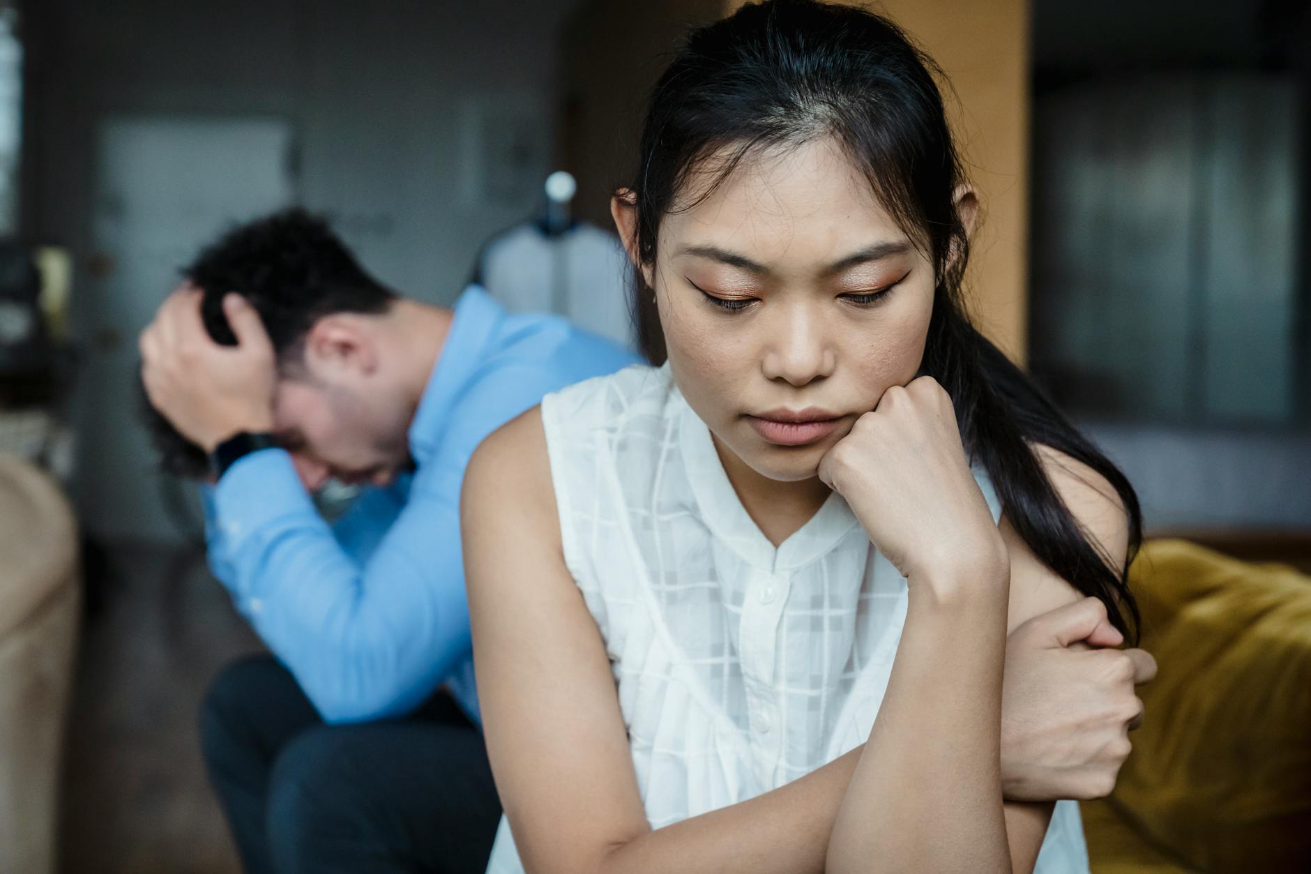 A couple experiencing relationship tension sitting silently on a sofa.