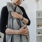 A senior woman holding a coat tightly, conveying emotions of loneliness and grief.