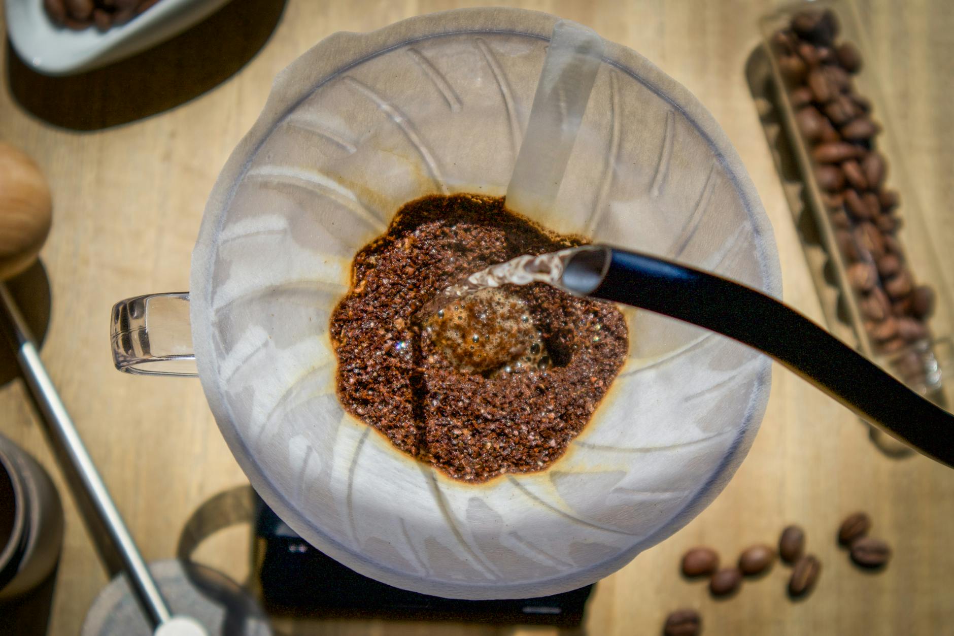 Overhead angle of pour over coffee with fresh grounds and hot water in a glass carafe.