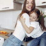 A joyful moment of a mother and daughter hugging in a modern kitchen setting.