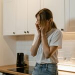 A woman in a modern kitchen looking distressed, emphasizing mental health awareness.