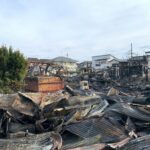 A scene showing destroyed buildings and debris after a large fire in an urban neighborhood.
