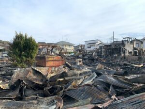 A scene showing destroyed buildings and debris after a large fire in an urban neighborhood.
