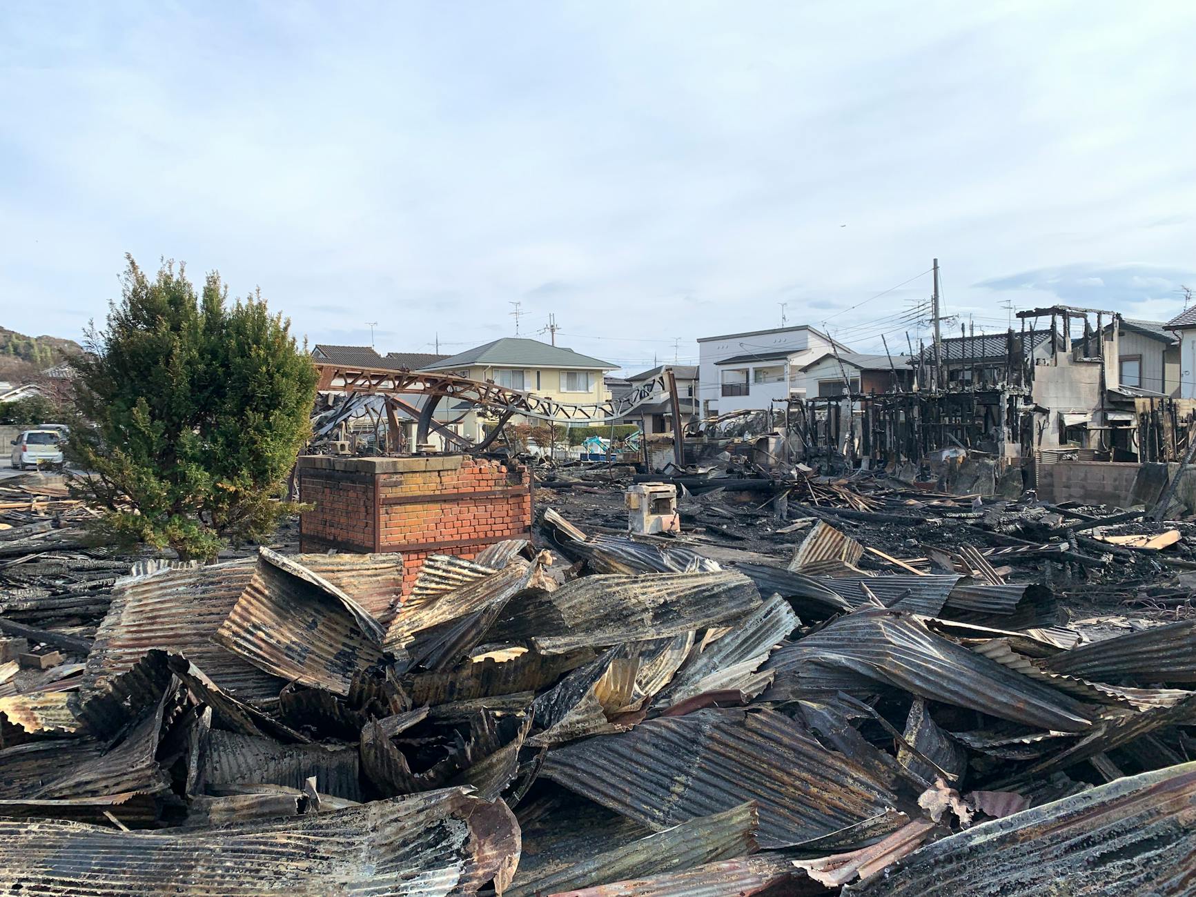 A scene showing destroyed buildings and debris after a large fire in an urban neighborhood.
