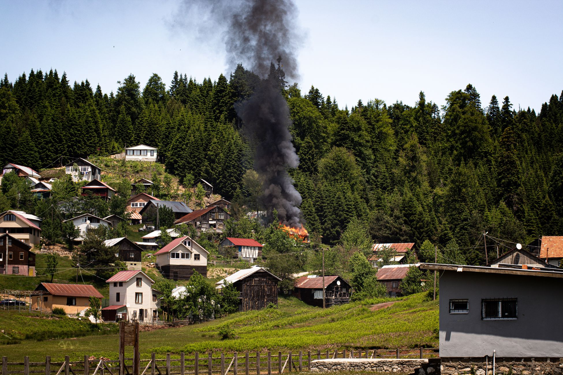 Smoke rises from a forested village fire in Sakarya, Türkiye. Captured in daylight showcasing village life and nature.