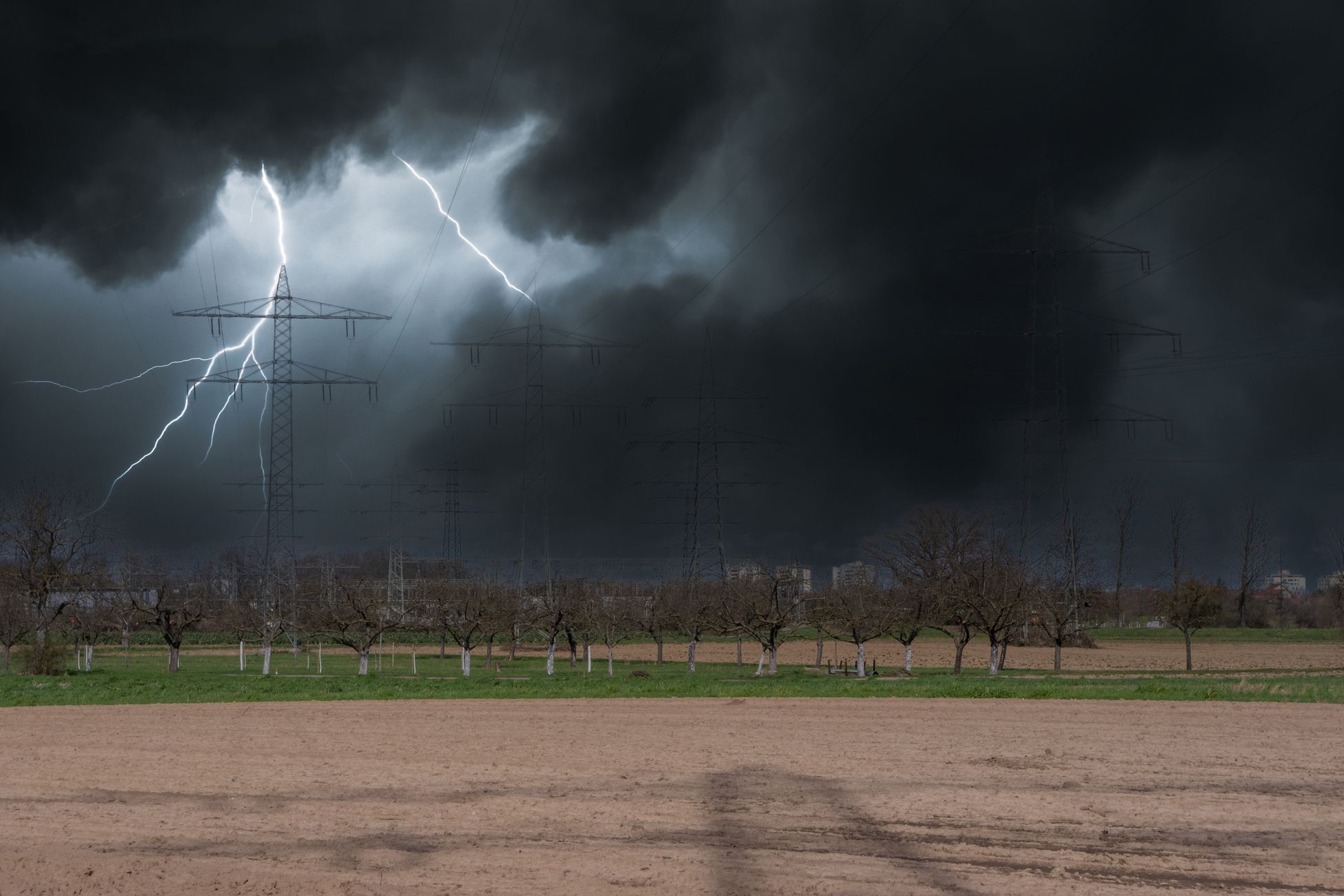 Intense lightning strikes during a storm over a countryside landscape with power lines.