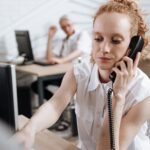Focused businesswoman making phone call at her desk in a modern office.