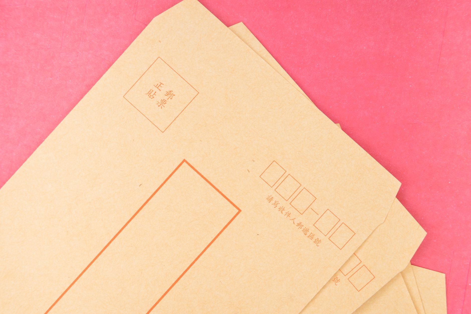Close-up of traditional Asian envelopes on a vibrant pink background, perfect for stationery needs.