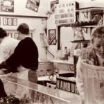Retro urban food stand with people serving fast food in sepia tone.