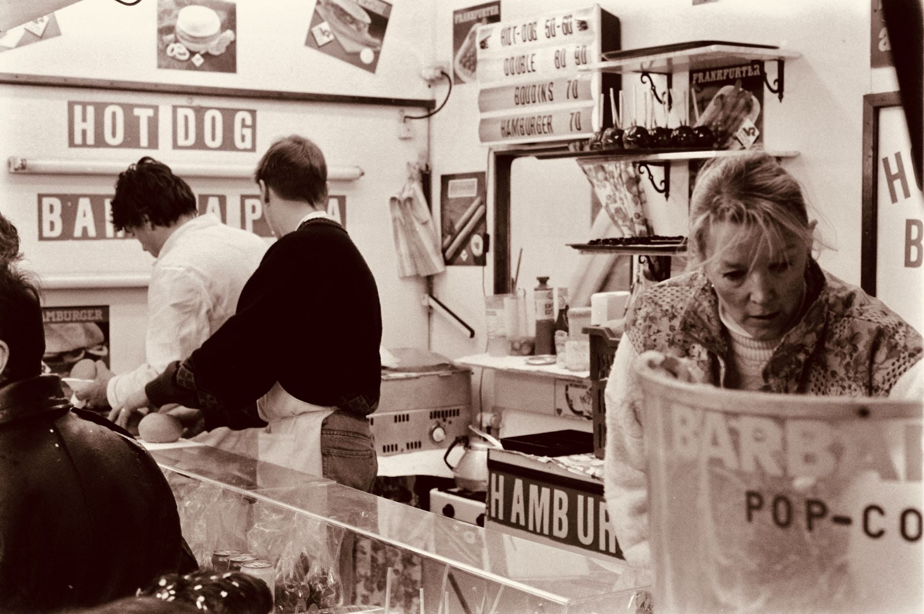 Retro urban food stand with people serving fast food in sepia tone.