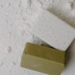Close-up of two natural bar soaps on a white powdered surface, emphasizing hygiene.