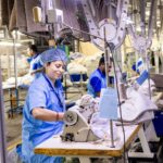 Close-up of textile factory workers operating sewing machines in an industrial setting.