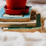 A stack of vintage books topped with a red pot, perfect for themes of literature and learning.