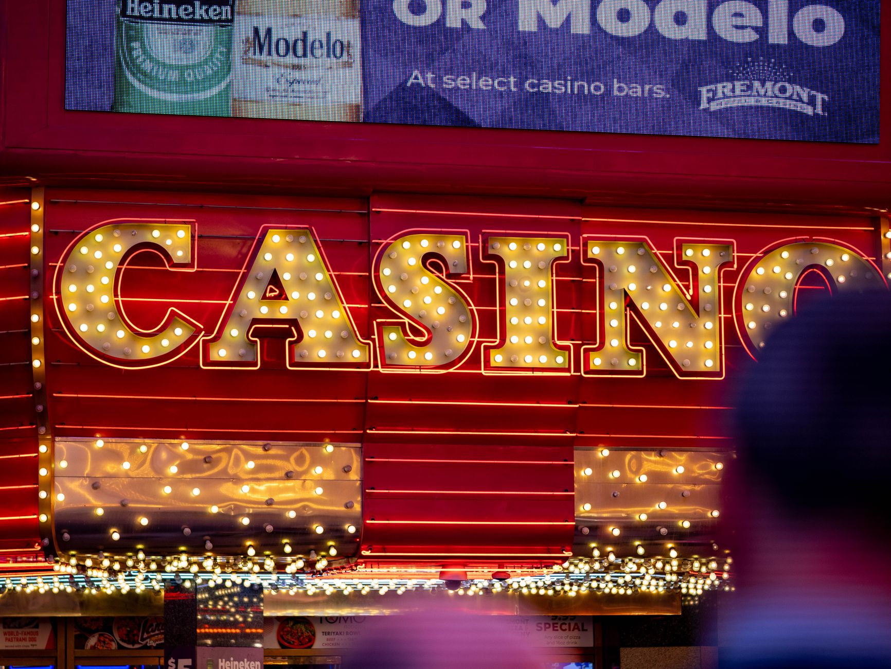 Illuminated casino sign glowing with bright lights during nighttime in a bustling city setting.