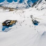 Aerial shot showcasing a ski resort surrounded by snow-capped mountains and skiers.