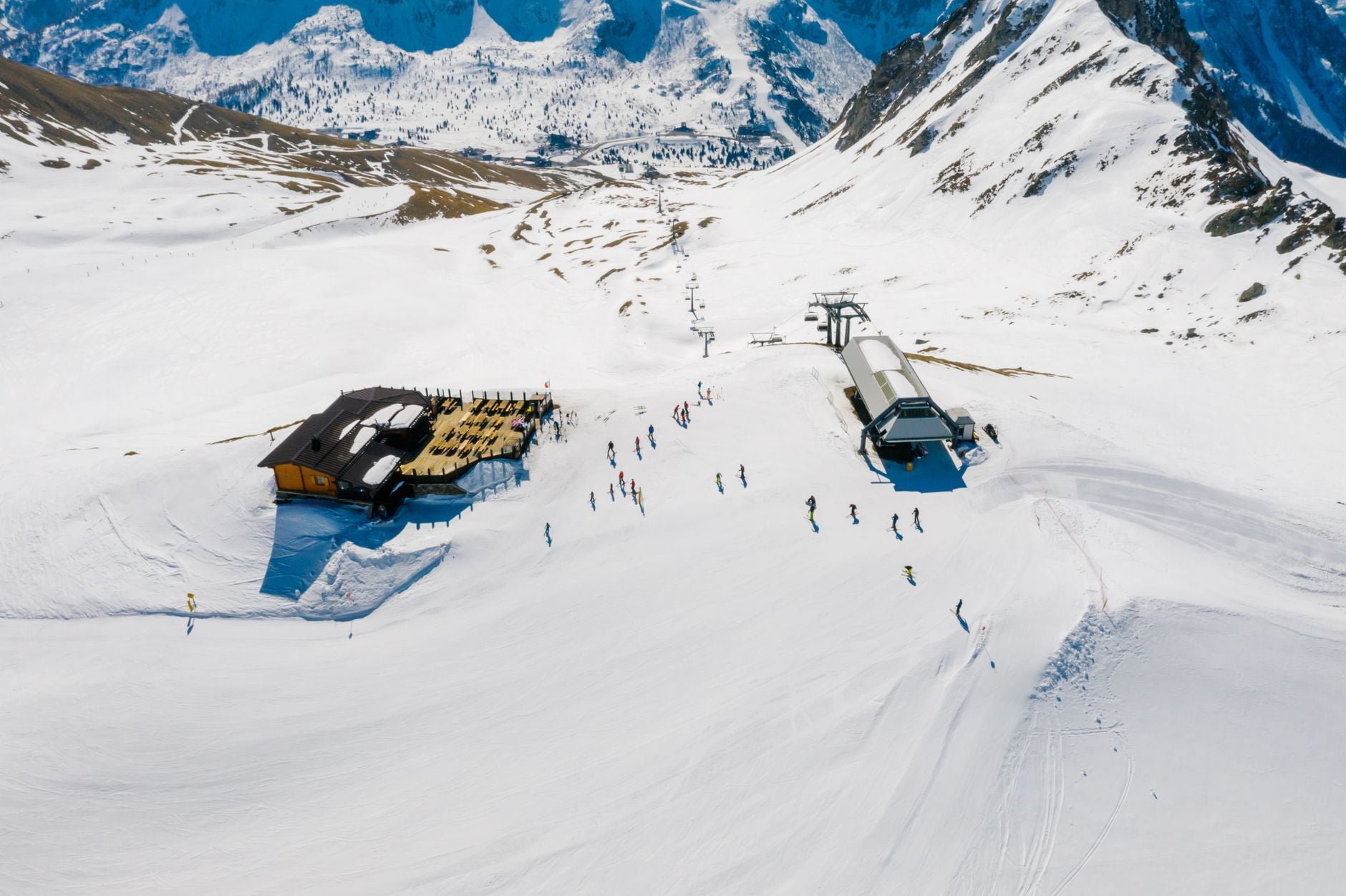 Aerial shot showcasing a ski resort surrounded by snow-capped mountains and skiers.