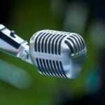 Classic chrome vintage microphone with defocused green outdoor background.