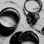 Elegant black and white image of engagement and wedding rings on textured background, symbolizing romance and commitment.