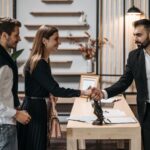 A professional meeting in a modern office with a couple shaking hands with a businessman.