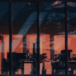 Moody office interior reflecting the evening cityscape through large windows.